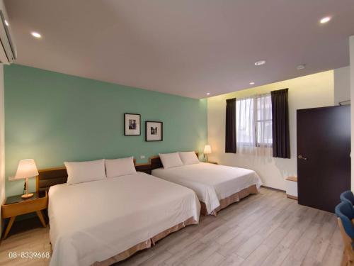 a bedroom with two beds and a green wall at TK Happiness 168 B&B in Donggang