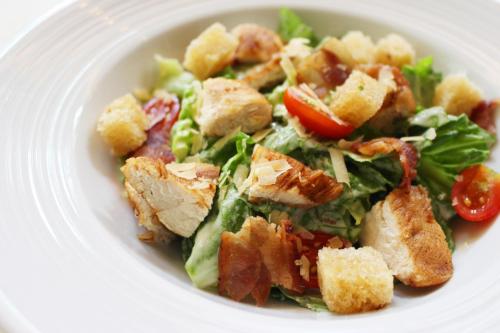 a white plate with a salad with bacon and lettuce at La Petite Salil Sukhumvit Thonglor 1 in Bangkok