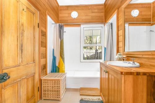 a bathroom with a tub and a sink and a window at Cooee Cottage in Blackheath