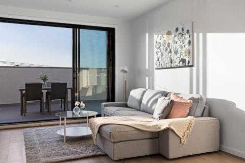 a living room with a couch and a table at Queensview168 Apartments Moonee Ponds in Melbourne