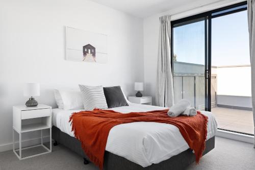 a bedroom with a large bed and a large window at Queensview168 Apartments Moonee Ponds in Melbourne