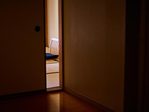 een open deur naar een kamer met een stoel bij Ito Yukitei in Ito