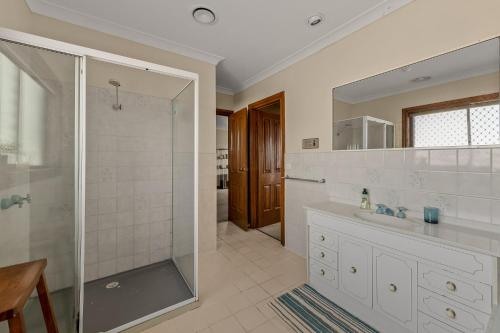 uma casa de banho com um chuveiro, um lavatório e um espelho. em Beachfront-private beach access and 180 degree bay views! em Chelsea