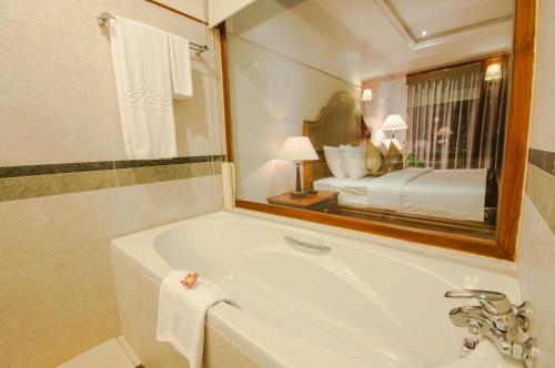 a bathroom with a tub and a bed in a mirror at Saem Siemreap Hotel in Siem Reap