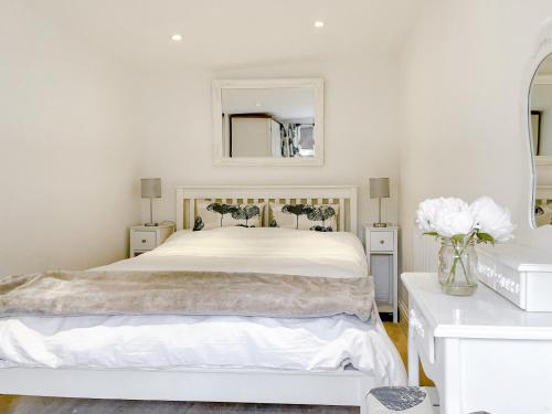 Dormitorio blanco con cama blanca y espejo en The Haven Lodge, en Clifton