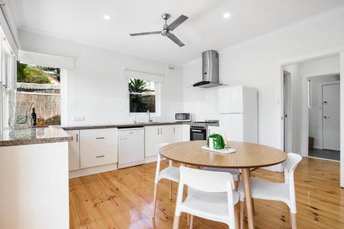 a kitchen with a wooden table and white cabinets at Relaxing 3BR Beachside Haven Grange in Grange