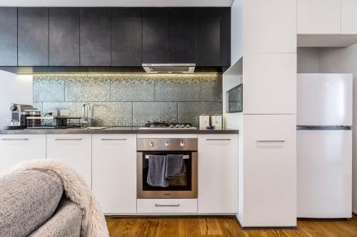 a kitchen with white cabinets and an oven at In the heart of Richmond - 1693 in Melbourne