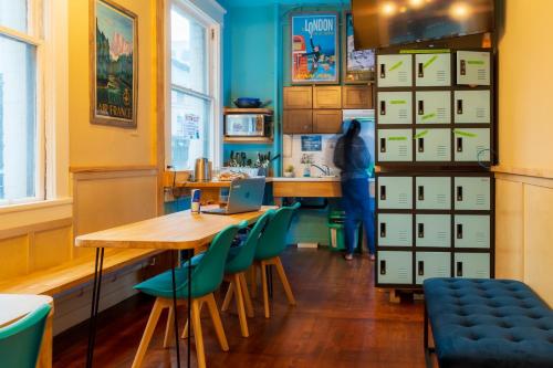 une cuisine avec une table en bois et des chaises vertes dans l'établissement The Cambie Hostel Seymour, à Vancouver