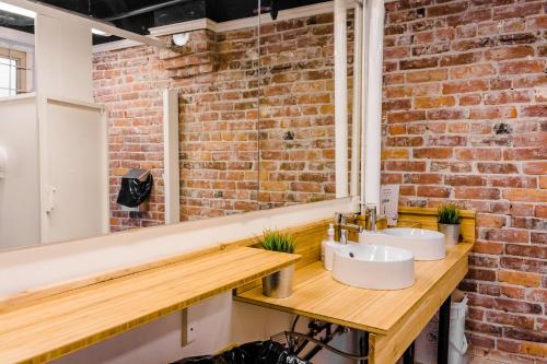 La salle de bains est pourvue de 2 lavabos et d'un mur en briques. dans l'établissement The Cambie Hostel Seymour, à Vancouver