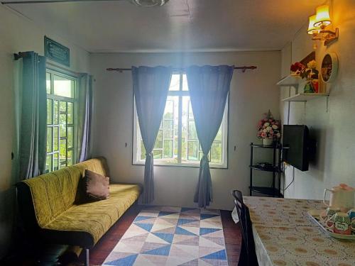 een woonkamer met een bank en een raam bij Rania Lovely Hut Homestay Kundasang in Kampong Kundassan