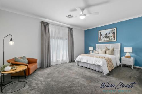 a bedroom with blue walls and a bed and a couch at Oceanview Escape by Wine Coast Holidays in Port Noarlunga South