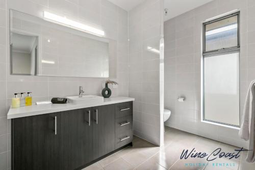 a white bathroom with a sink and a mirror at Oceanview Escape by Wine Coast Holidays in Port Noarlunga South