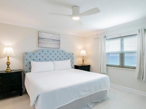 Un dormitorio blanco con una cama y un ventilador de techo. en Regency Towers #708 West, en Pensacola Beach