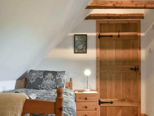 Schlafzimmer mit einem Bett und einer Holztür in der Unterkunft Annies Cottage in Edinbain