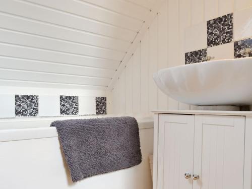 ein Badezimmer mit einem weißen Waschbecken und einer Theke in der Unterkunft Annies Cottage in Edinbain