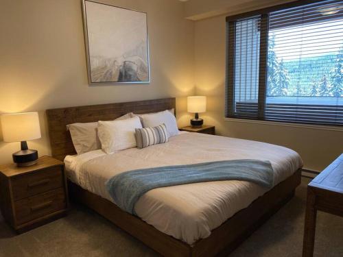 a bedroom with a bed with two lamps and a window at Cozy Modern Ski-in/Ski-out, Hot Tub, Alpine Home in Sun Peaks