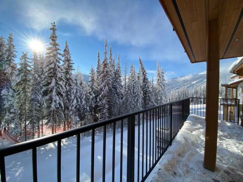 Cozy Modern Ski-in/Ski-out, Hot Tub, Alpine Home في صن بيكس: شرفة منزل به أشجار مغطاة بالثلج