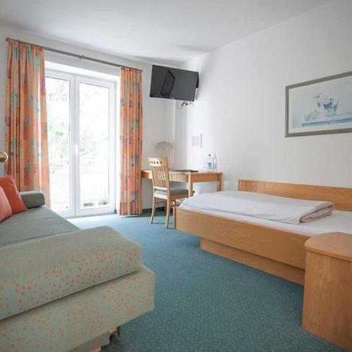 - une chambre avec 2 lits, une table et un bureau dans l'établissement Hotel Egger-Stüberl, à Schechen
