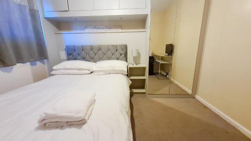 um quarto com uma cama com lençóis brancos e um espelho em Room in Guest room - Newly Built Private Ensuite In Dudley Westmidlands em Dudley