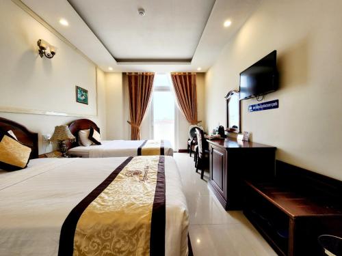 a hotel room with two beds and a television at Marguerite Dalat Hotel in Da Lat