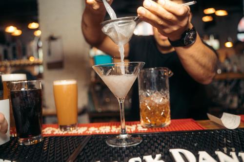 a bartender is mixing a drink in a martini glass at The Cambie Hostel Seymour in Vancouver