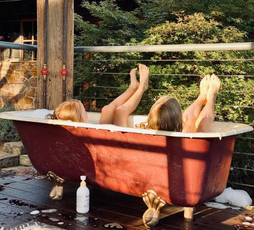 two people laying in a bath tub with their hands up at Stone Creek Cottage in Barwite