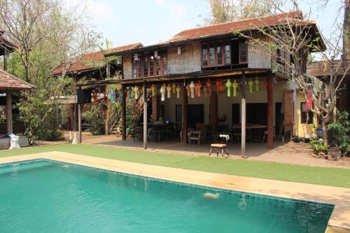 a house with a swimming pool in front of a house at Capital O 75421 Baan Singkham Boutique Resort in Chiang Mai