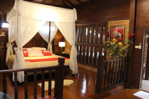 a bedroom with a bed with a canopy at Capital O 75421 Baan Singkham Boutique Resort in Chiang Mai
