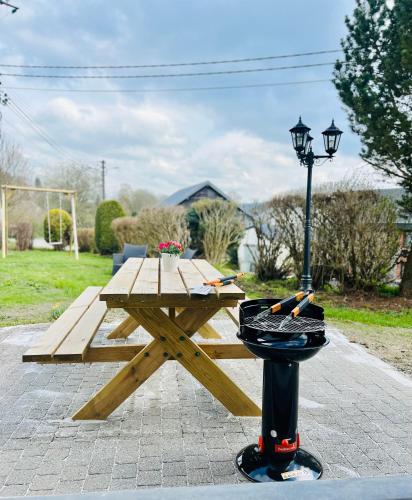 a wooden picnic table with a hat on top of it at La Balade enchantée- gîte 6 personnes - Ardenne Belge in Tenneville