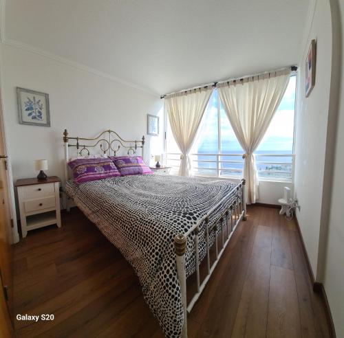 a bedroom with a bed with purple pillows and a window at Euromarina 2 Reñaca Vista al Mar in Viña del Mar
