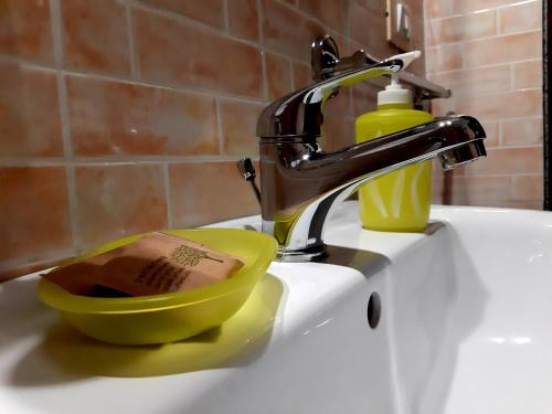 - un lavabo avec un robinet et un bol jaune avec une bouteille de savon dans l'établissement B&B La Nicchiarica, à Muro Leccese