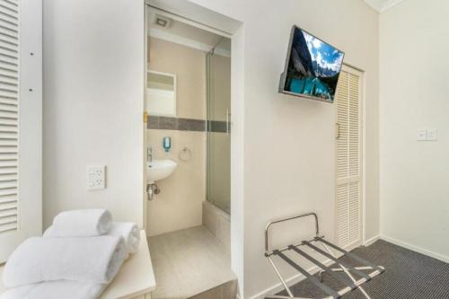 a bathroom with a sink and a television on a wall at Ramada by Wyndham, Hamilton City Center in Hamilton
