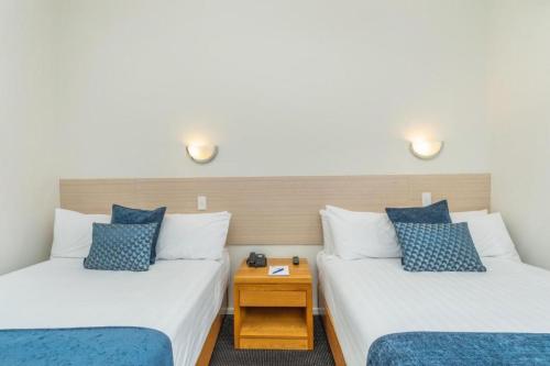two beds with blue and white pillows in a room at Ramada by Wyndham, Hamilton City Center in Hamilton