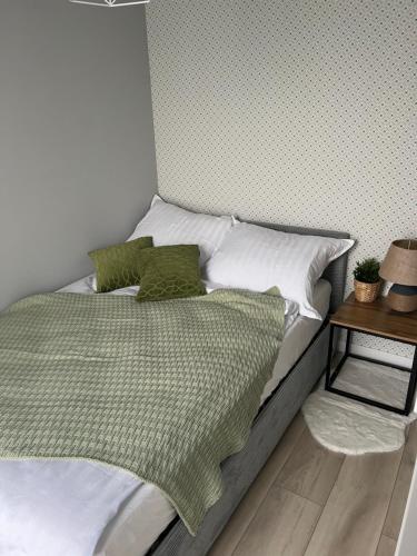łóżko z białą i zieloną pościelą oraz stolikiem. w obiekcie Marcinkowskiego 11 - 3 w mieście Katowice