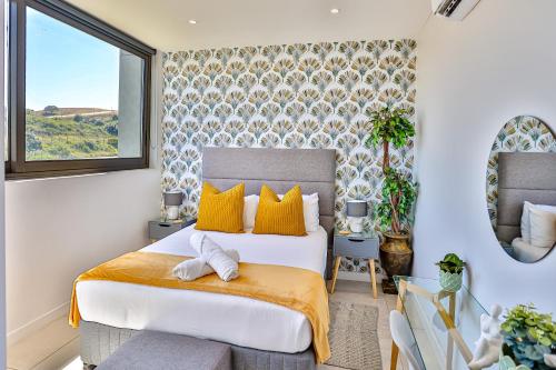 a bedroom with a bed with yellow pillows and a window at Zimbali Lakes Boulevard Suites 103 in Ballito