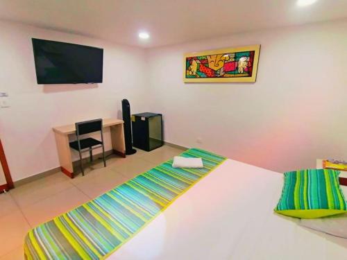 a bedroom with a bed and a desk and a television at HOTEL DON QUIJOTE in Pereira