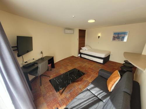 a living room with a couch and a bed at City of Sails Motel in Auckland