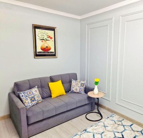 sala de estar con sofá gris y almohadas amarillas en НОВАЯ - 1 комнатная квартира!, en Taraz