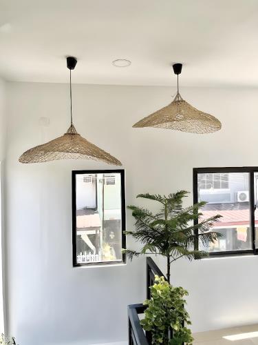 two lights hanging from the ceiling in a room with a plant at New Modern Suite Near Airport & Beach in Sudtungan