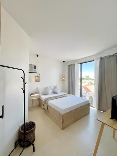 - une chambre blanche avec un lit et une grande fenêtre dans l'établissement New Modern Suite Near Airport & Beach, à Sudtungan