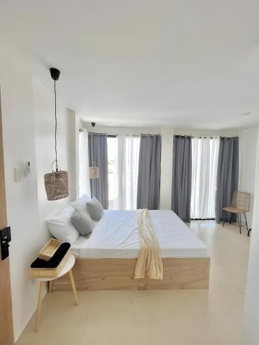 a white bedroom with a large bed and a chair at New Modern Suite Near Airport & Beach in Sudtungan