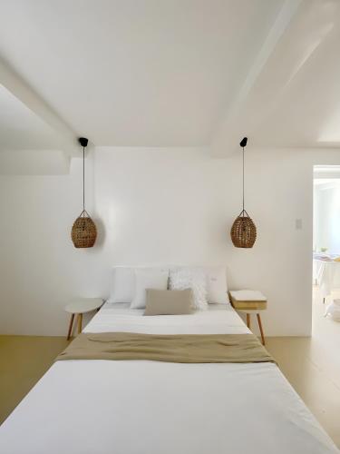 a white bedroom with a bed and two chairs at New Modern Suite Near Airport & Beach in Sudtungan