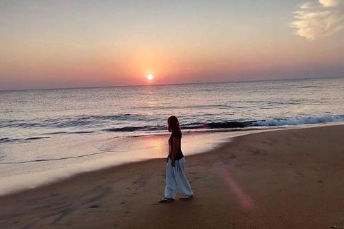 a woman standing on the beach watching the sunset at Nayan's Paradise in Kottanitivu