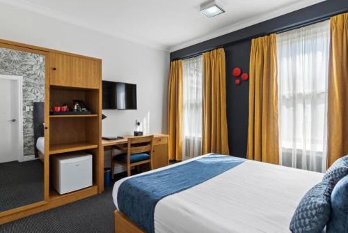 a hotel room with a bed and a desk at Ramada by Wyndham, Hamilton City Center in Hamilton