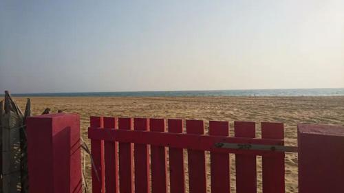 a red fence on a beach with the ocean in the background at Nayan's Paradise in Kottanitivu