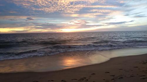 a sunset on the beach with the ocean at Nayan's Paradise in Kottanitivu