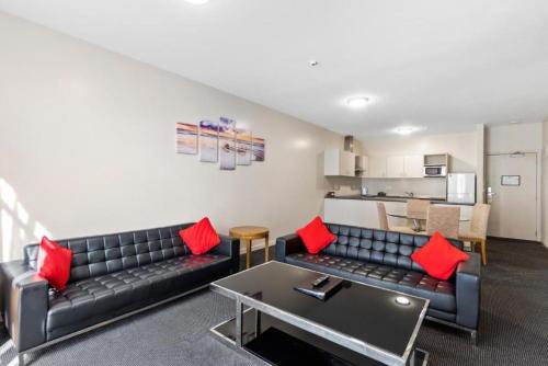 a living room with a black couch and red pillows at Ramada by Wyndham, Hamilton City Center in Hamilton