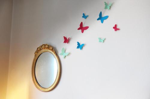 un espejo en una pared con mariposas. en Allegra House, en Milán