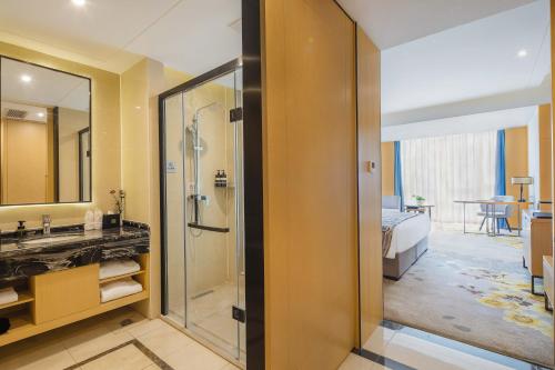 ein Bad mit einer Dusche, einem Waschbecken und einem Spiegel in der Unterkunft United Kingson HoteL in Chengdu