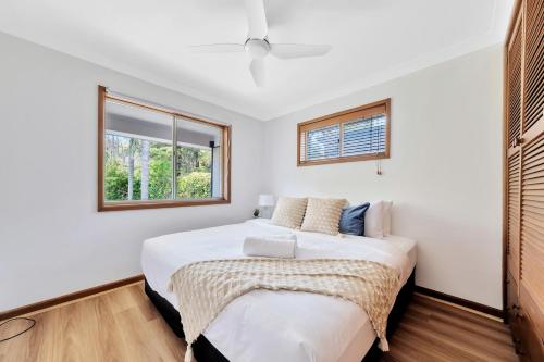 a bedroom with a bed and two windows at Bateau Family Retreat - Magical sunset views in Bateau Bay